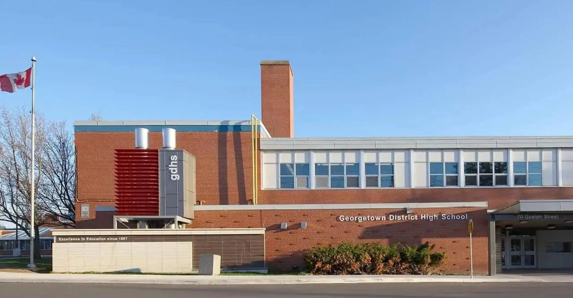 L'edificio in mattoni della Georgetown District High School con un'alta ciminiera e una bandiera canadese in primo piano.