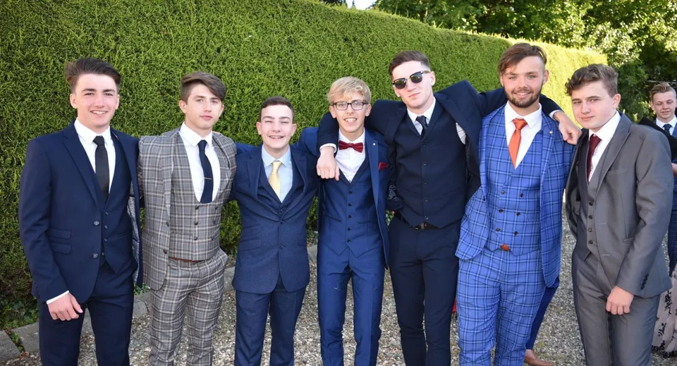 Un gruppo di persone si trova nel giardino del St. Patrick's College durante un evento formale.