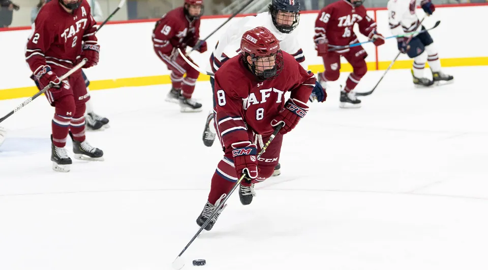 Un giocatore di hockey su ghiaccio della Taft School controlla il disco sulla pista.