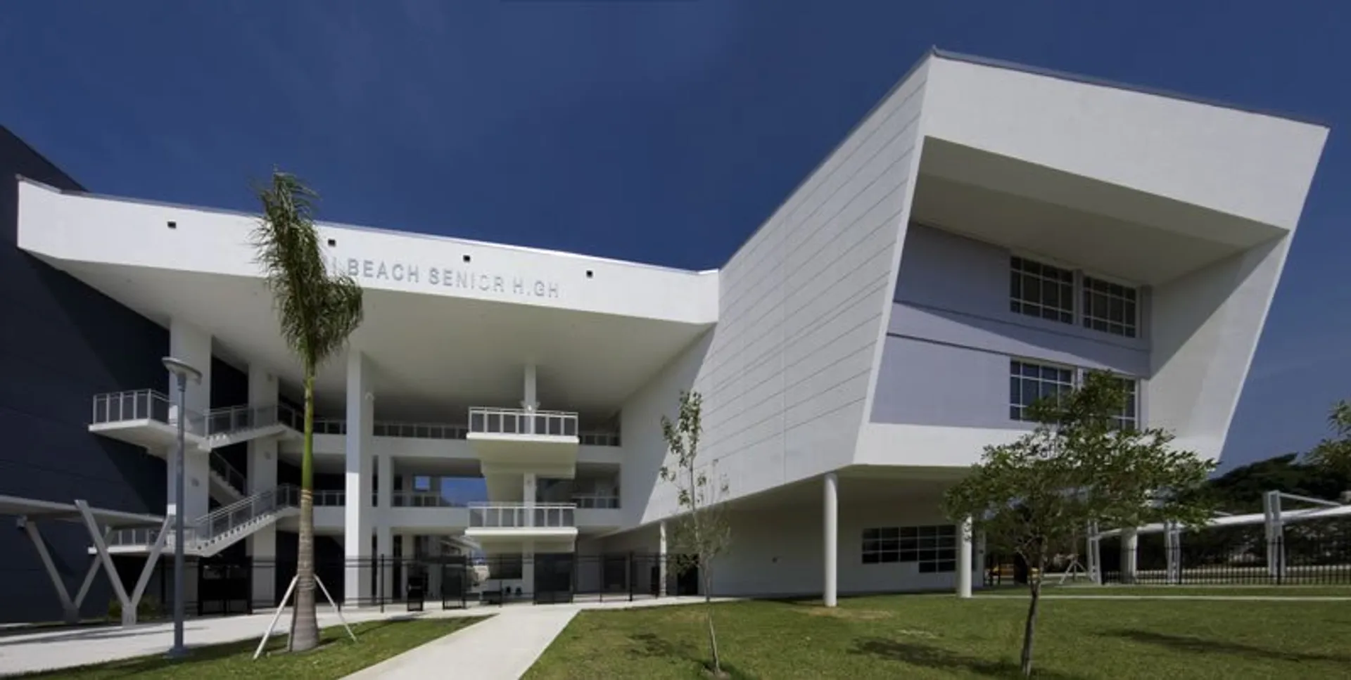 Un moderno edificio scolastico a più piani della Miami-Dade County Public School con design minimalista e aree verdi ben curate.