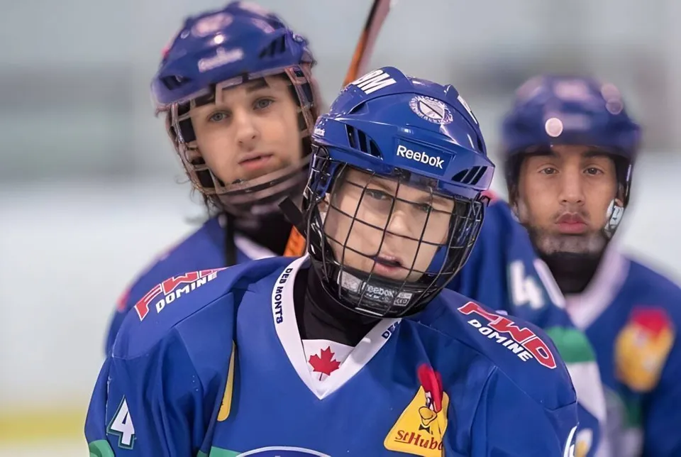 Tre giocatori di hockey in divisa blu sono sul ghiaccio nel palazzetto della École Polyvalente des Monts.