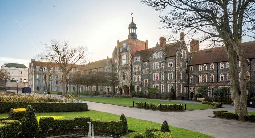 Il cortile interno del Brighton College mostra un prato ben curato e edifici storici sotto un cielo limpido.
