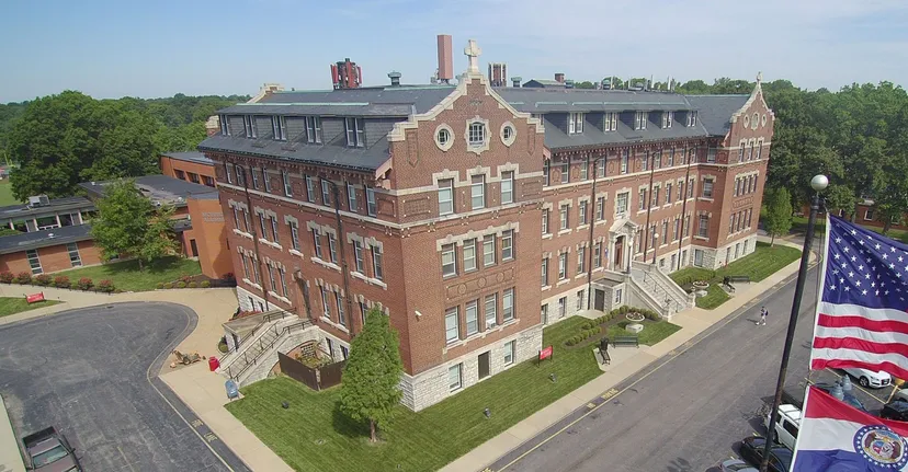 L'edificio decorativo in mattoni della Chaminade College Preparatory School sorge circondato da aree verdi e da una strada.