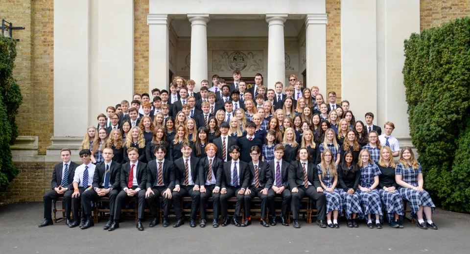 Un gruppo di studenti del Bishop’s Stortford College posa in abito formale davanti a un edificio con colonne.