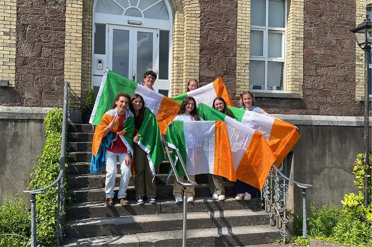 Gruppo di studenti sui gradini di un edificio mostra bandiere irlandesi