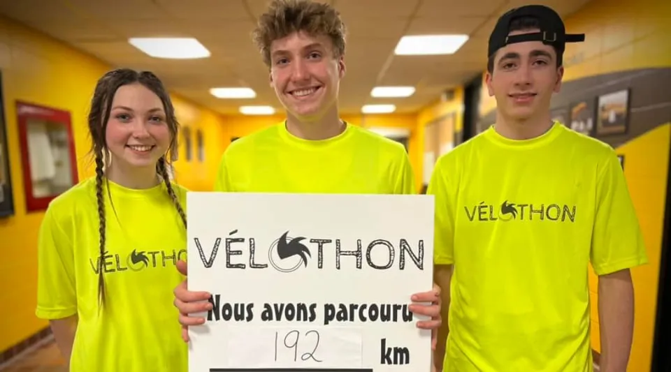 Tre studenti della Polyvalente Louis-J.-Robichaud indossano t-shirt gialle VELOTHON e tengono un cartello con la scritta 192 km.