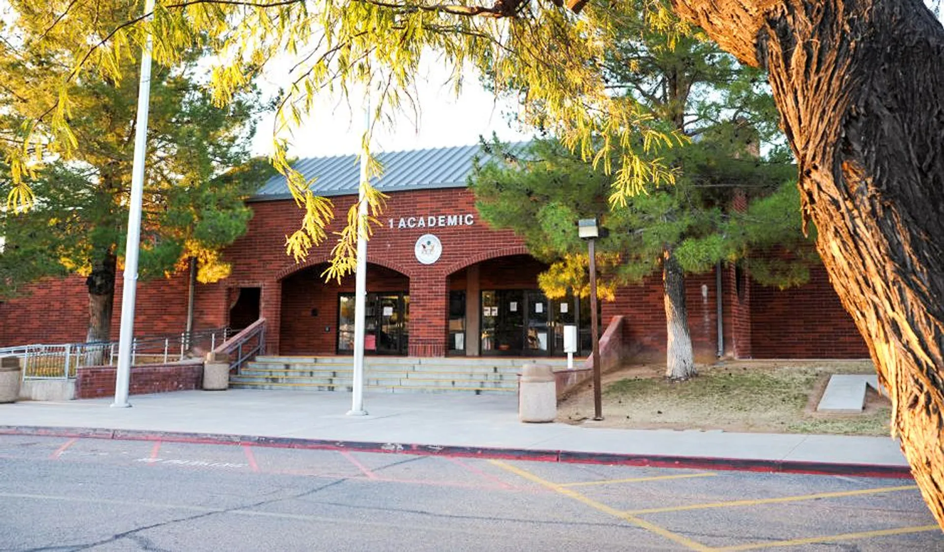 L'edificio con tetto rosso e insegna Academic nel Mesa Unified School District è circondato da alberi e ha un sentiero pavimentato che conduce all'ingresso.