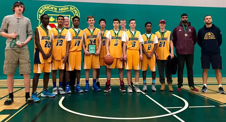 Un gruppo di studenti della John McCrae Secondary School in maglia gialla si trova insieme sul campo da basket.