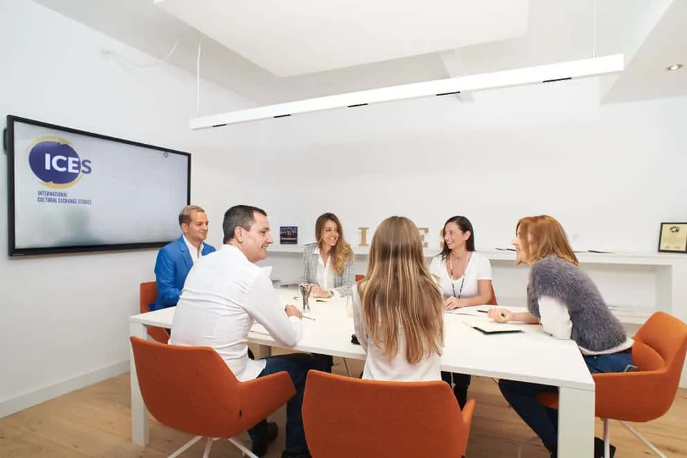 Grupo de personas reunidas alrededor de una mesa blanca en una oficina con el logotipo ICES
