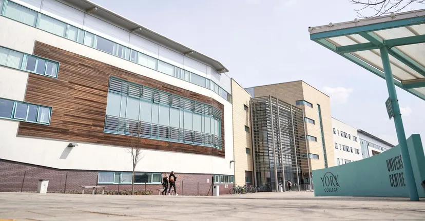 L'edificio moderno del York College con facciata in legno e vetro e un'insegna turchese in primo piano.
