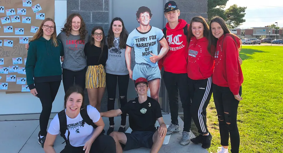 Un gruppo di studenti è in piedi davanti all'edificio della Lambton Central Collegiate & Vocational School e posa per una foto.