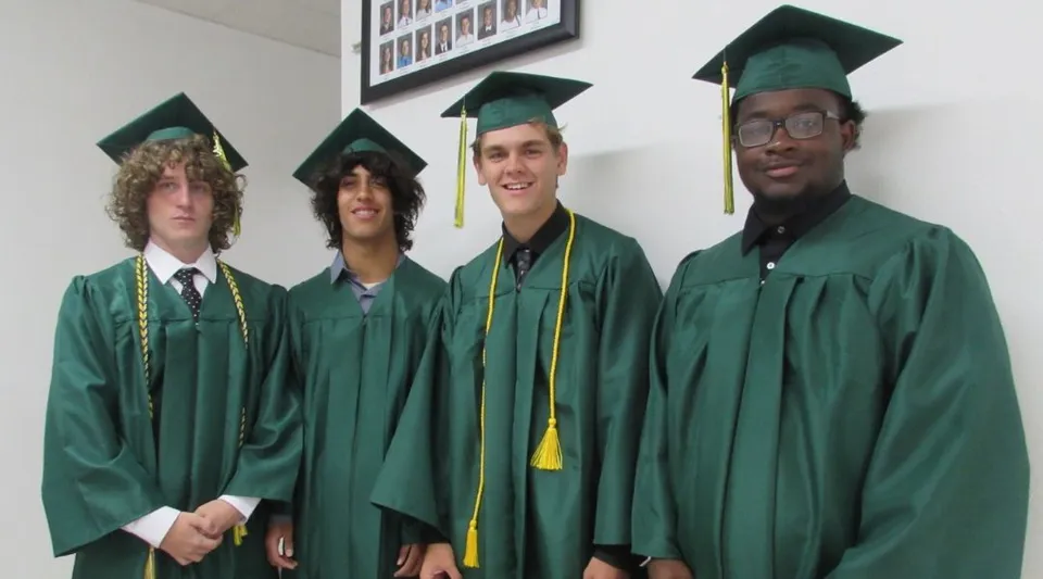 Quattro studenti in toga verde festeggiano il loro diploma alla Metro East Lutheran High School.