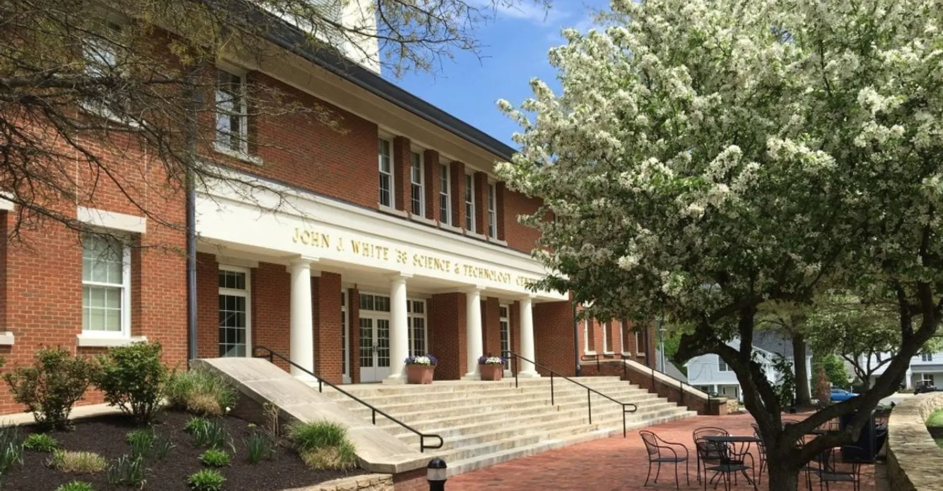L'edificio in mattoni con ingresso a colonne nel campus della Cheshire Academy è circondato da alberi in fiore e un sentiero pavimentato.