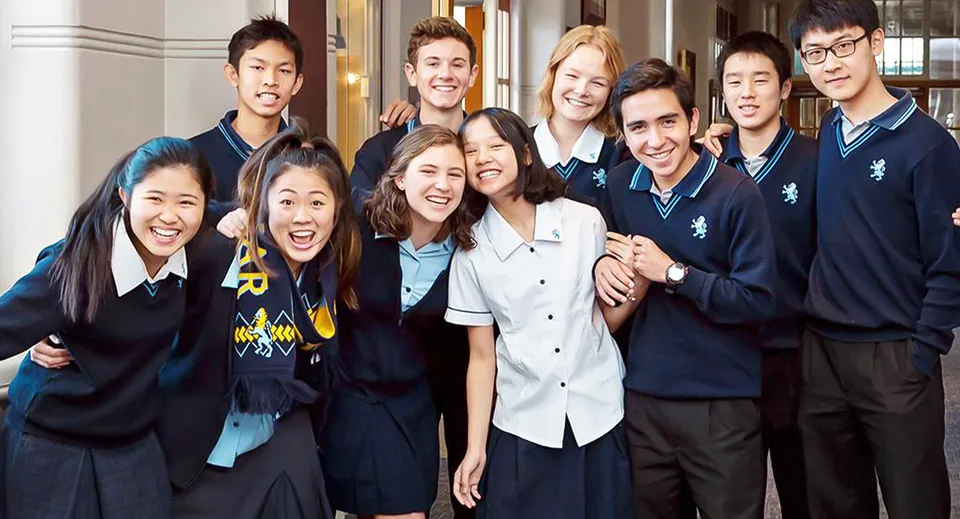 Un gruppo di studenti in uniforme scolastica posa in un corridoio nel campus della Mount Albert Grammar School.