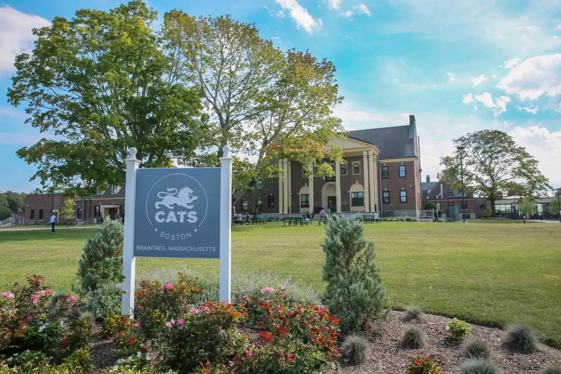 Un cartello della CATS Academy Boston si trova sul prato davanti all'edificio in mattoni della scuola.