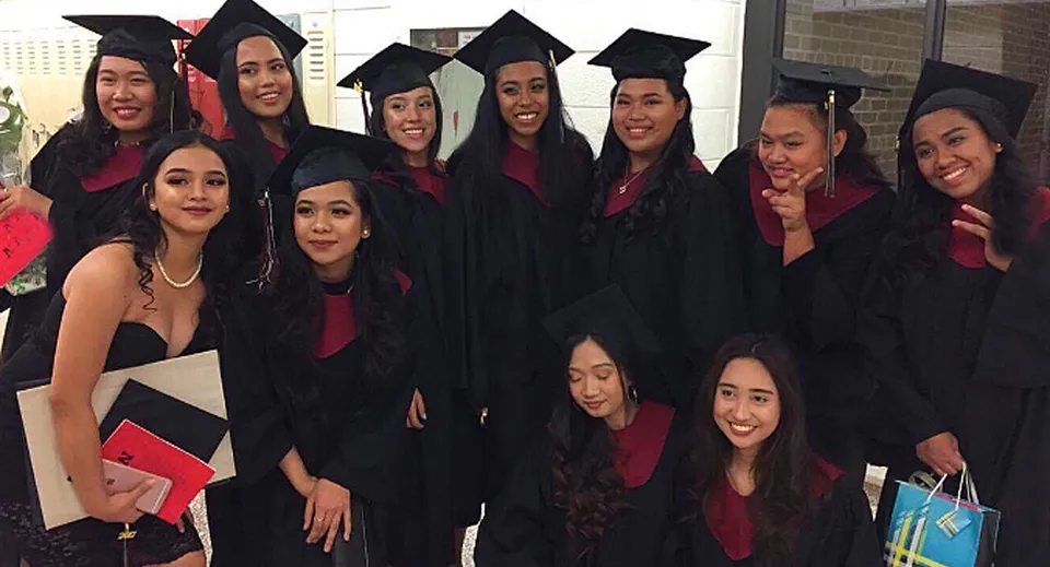 Un gruppo di studentesse sorridenti in abito da diploma si trova davanti all'edificio scolastico della Newtonbrook Secondary School.