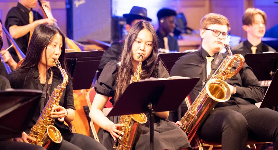 Un gruppo di musicisti, tra cui dei sassofonisti, si esibisce sul palco del Bishop’s Stortford College.