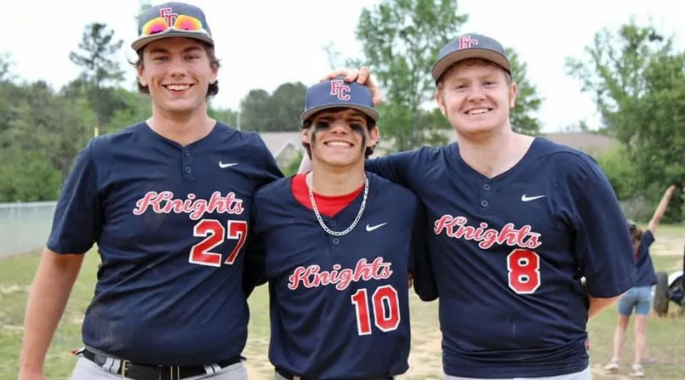 Tre studenti della Faith Christian School in divisa da baseball sono insieme su un prato all'aperto.