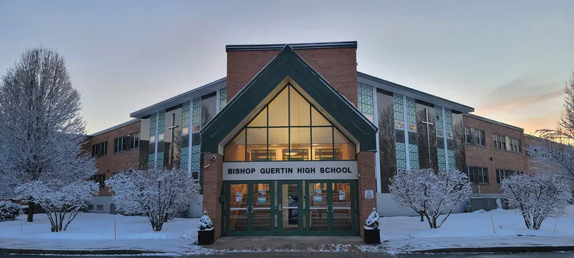 L'edificio in mattoni con tetto a due falde della Bishop Guertin High School circondato da alberi innevati.