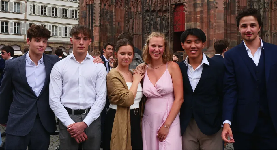 Un gruppo di persone si trova davanti all'edificio storico del Collège Episcopal Saint Étienne.