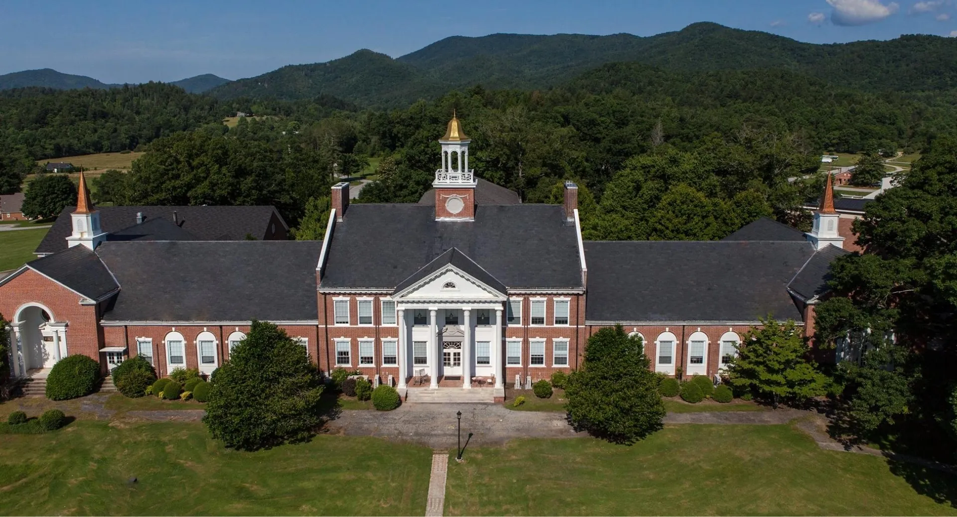 L'edificio in mattoni con la torre dell'orologio della Rabun Gap-Nacoochee School è circondato da aree verdi e montagne.