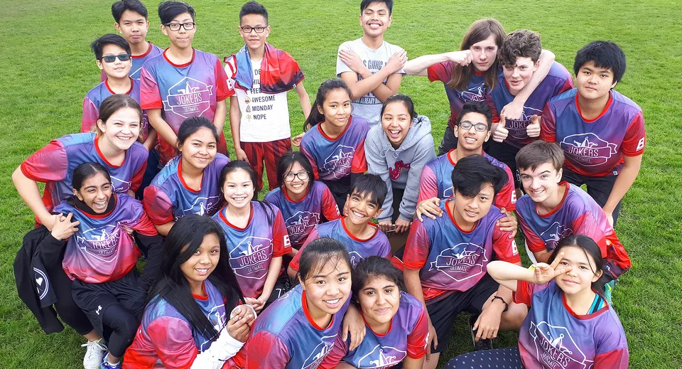 Studenti della John Oliver Secondary School posano insieme nella squadra sportiva su un campo da calcio.