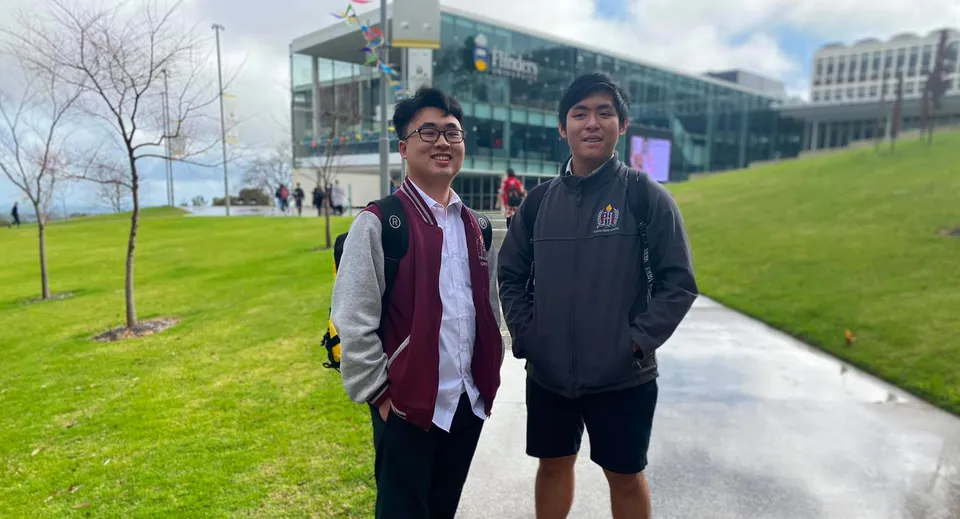 Due studenti in piedi davanti a un edificio moderno nel campus della Findon High School con un prato sullo sfondo.
