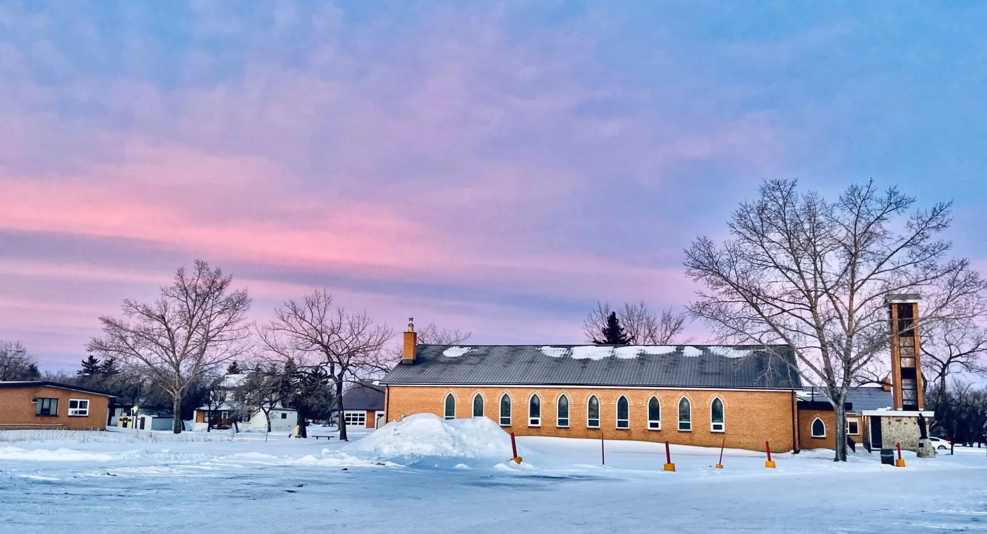 L'Athol Murray College of Notre Dame mostra un edificio in mattoni con un bosco invernale innevato e un cielo colorato sullo sfondo.