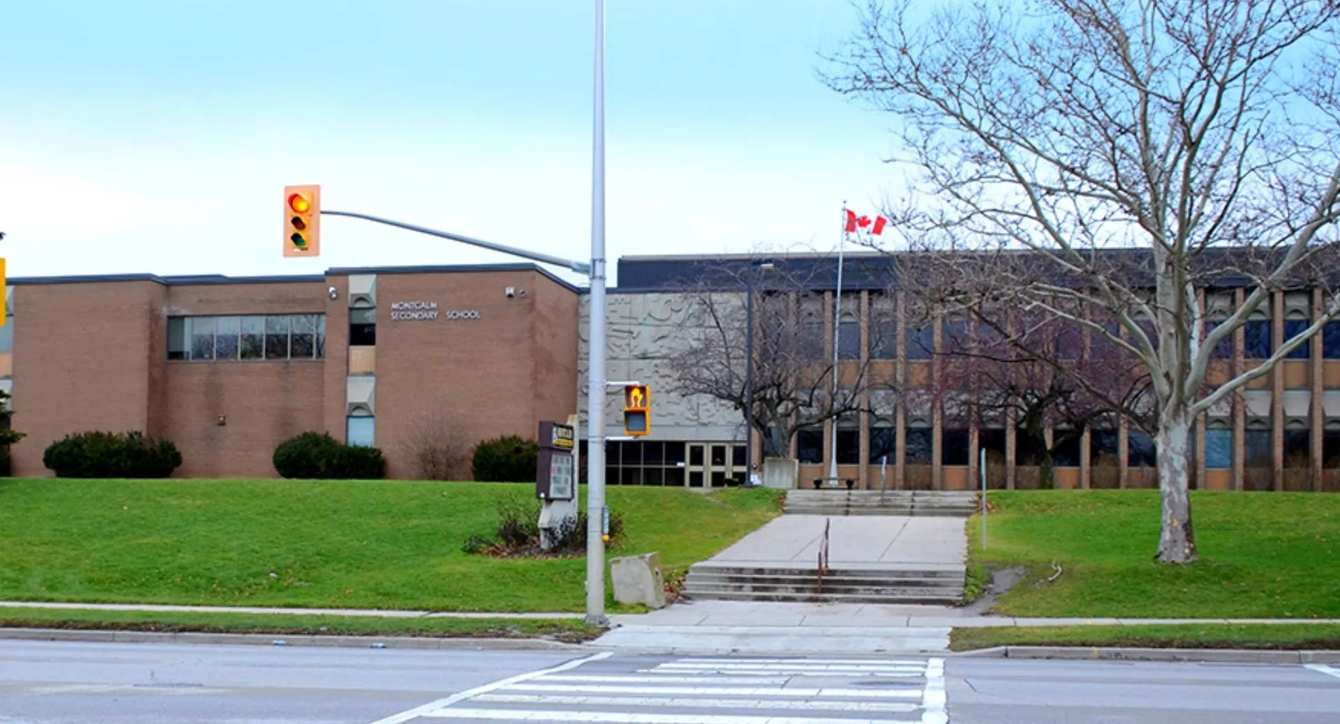 L'edificio in mattoni della Montcalm Secondary School con una bandiera canadese sul davanti e alberi sullo sfondo.