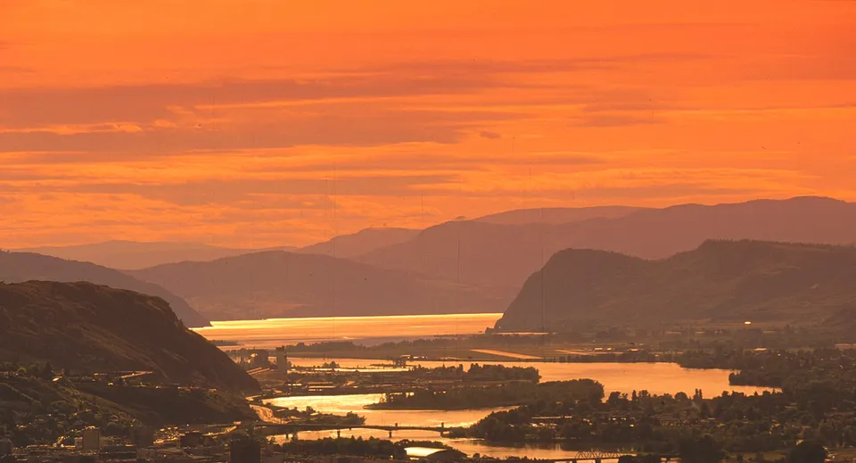 Un paesaggio fluviale a Kamloops al tramonto sotto un cielo arancione vicino alla Westsyde Secondary School.