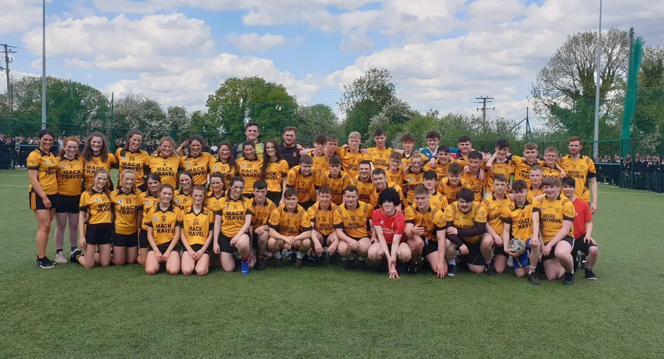 Un grande gruppo di studentesse in divisa gialla posa per una foto di gruppo sul prato della Cornafulla National School.