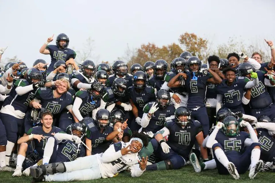Un gruppo di giocatori di football in divisa sta sul campo da gioco della St. Mary's Ryken High School.