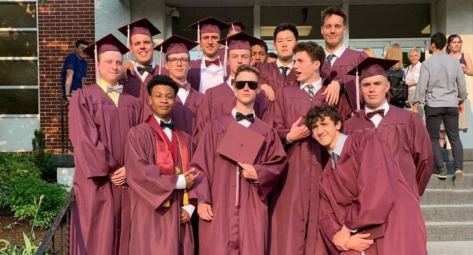 Un gruppo di diplomati della Faith Christian Academy (PA) posa in toga rossa davanti a un edificio in mattoni.