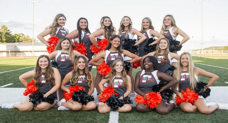 Un gruppo di cheerleader in uniformi coordinate posa sul campo sportivo del Davis School District.