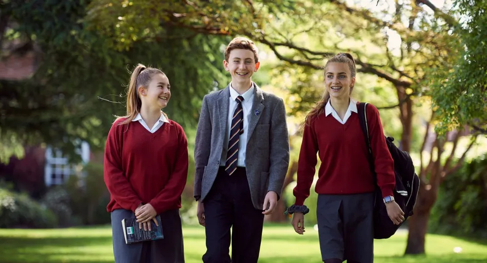 Tre studenti del Lord Wandsworth College camminano insieme su un sentiero erboso del campus.