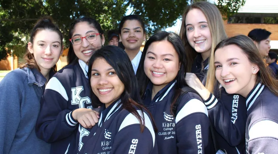 Un gruppo di studentesse del Kiara College in divisa sportiva posa all'aperto davanti ad alcuni alberi.
