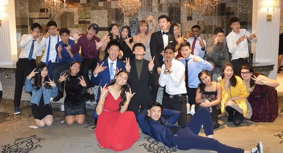 Un gruppo di persone in abito formale si riunisce in una sala sfarzosa nel campus della Milliken Mills Secondary School.