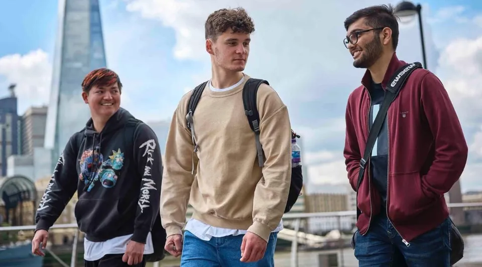 Tre giovani si trovano in un contesto urbano con vista sulla città nel campus del David Game College Liverpool.
