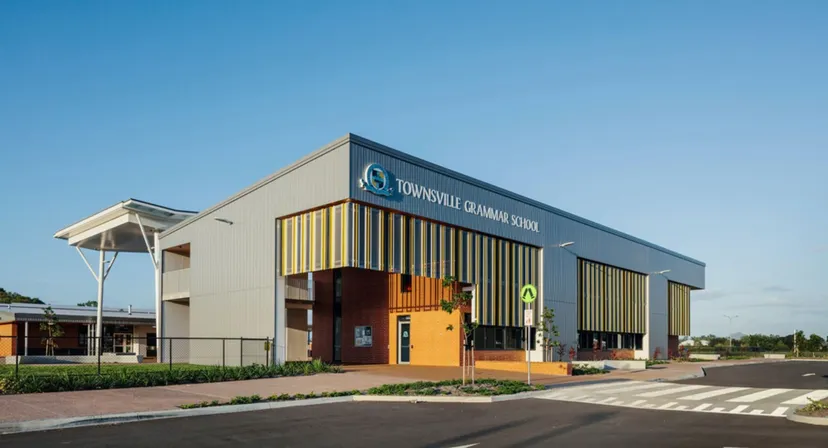 L'edificio scolastico moderno della Townsville Grammar School con un grande logo e un parcheggio in primo piano sotto un cielo limpido.