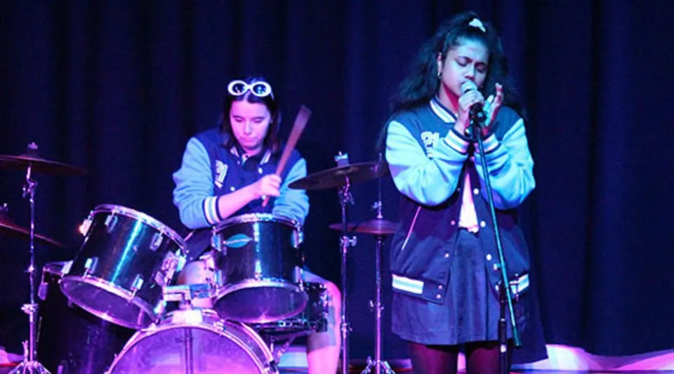Due studenti del Southern River College si esibiscono insieme sul palco con batteria e canto.