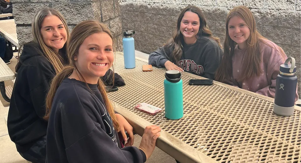 Quattro studentesse della Hamilton High School posano insieme all'aperto davanti a un muro di cemento.