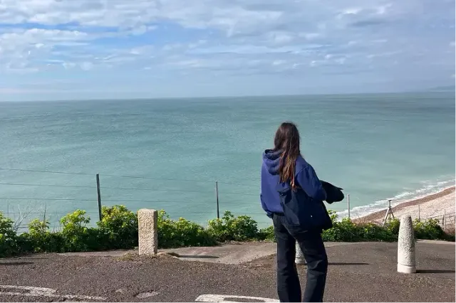 Studentessa di spalle osserva il mare da un punto panoramico sulla costa