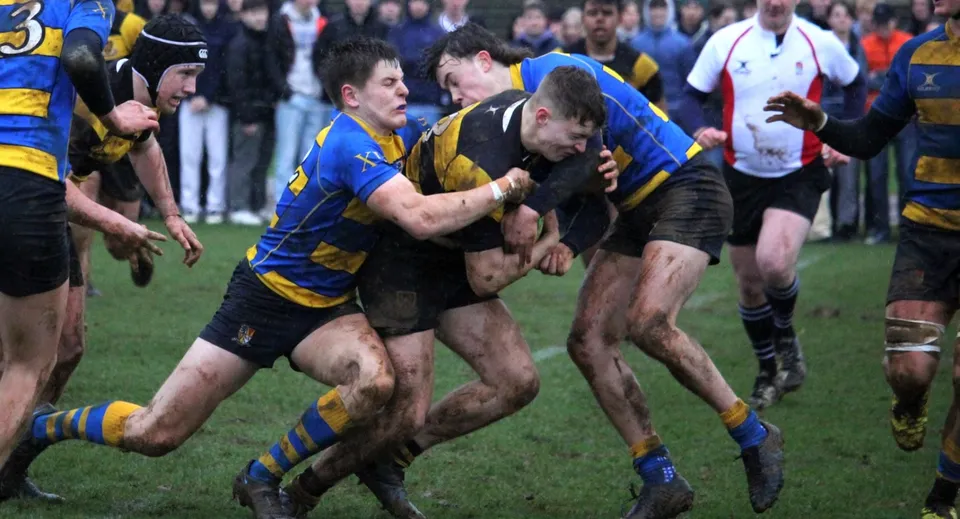Due giocatori di rugby con maglie avversarie effettuano un contatto fisico in campo durante una partita alla Stowe School.