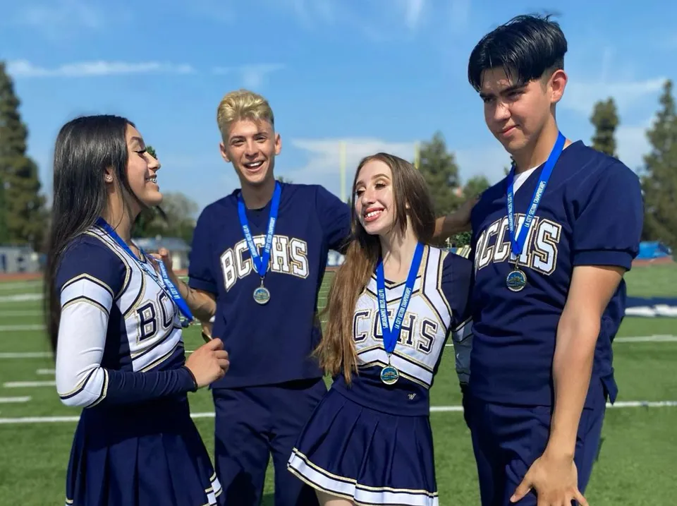 Quattro studenti e studentesse della Birmingham Community Charter High School sono insieme sul campo da gioco con le loro divise sportive blu.