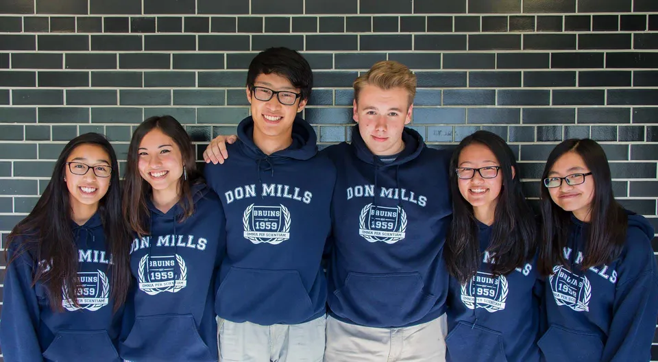 Un gruppo di studenti del Don Mills Collegiate Institute indossa felpe con cappuccio blu con la scritta Don Mills davanti a una parete piastrellata.