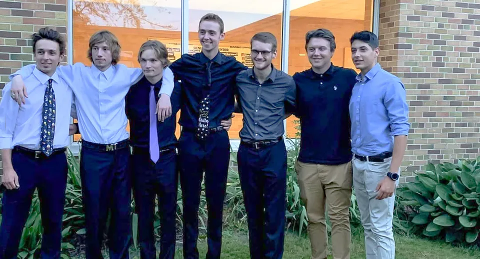 Un gruppo di studenti sta davanti a un edificio in mattoni con una parete arancione nel campus della Tilbury District High School.
