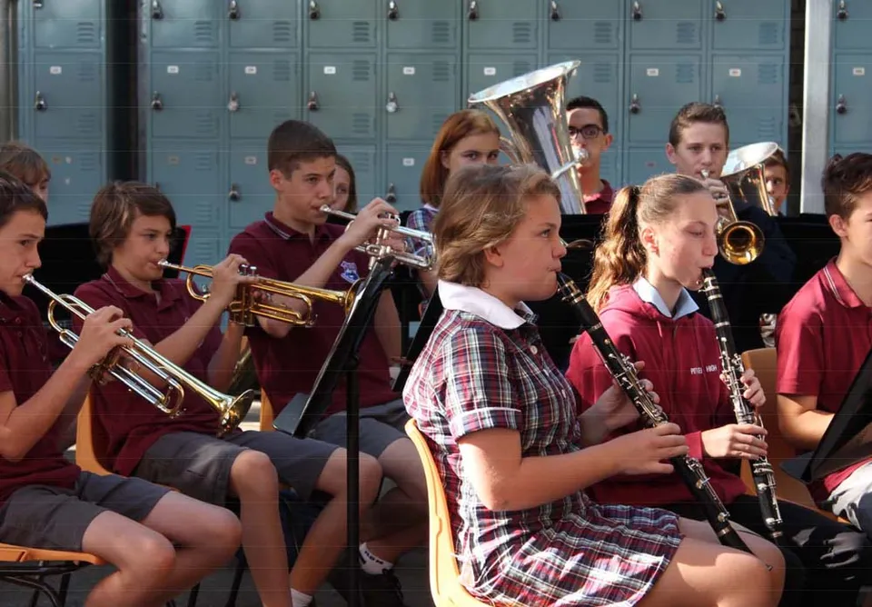 Studenti della Pittwater High School si trovano nel corridoio della scuola con strumenti musicali davanti agli armadietti.