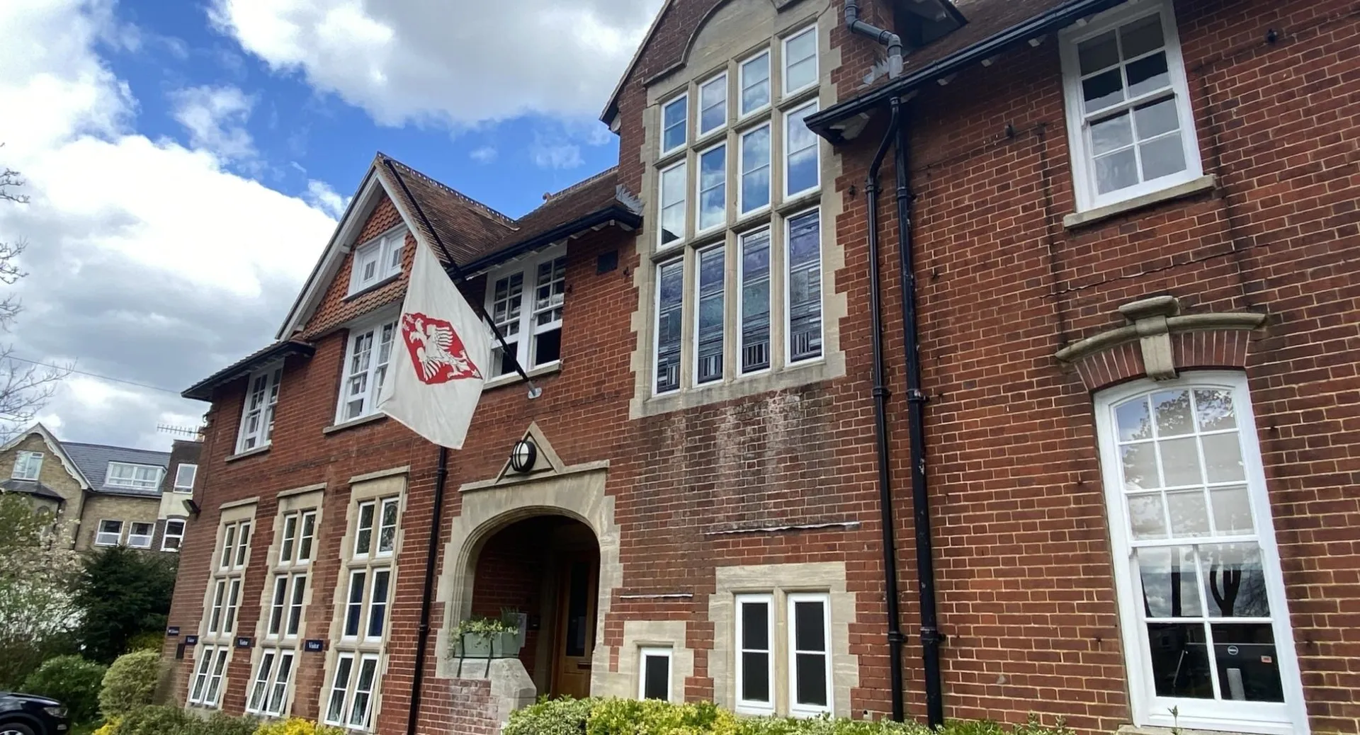 L'edificio in mattoni a più piani della Godolphin School con grandi finestre e un ingresso principale ad arco sotto un cielo nuvoloso.