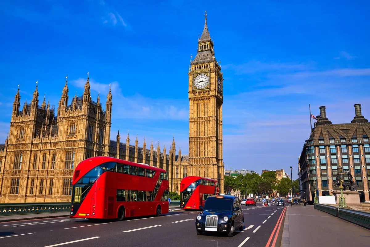 El Big Ben y el Palacio de Westminster en Londres con autobuses rojos de dos pisos y un taxi negro en el puente
