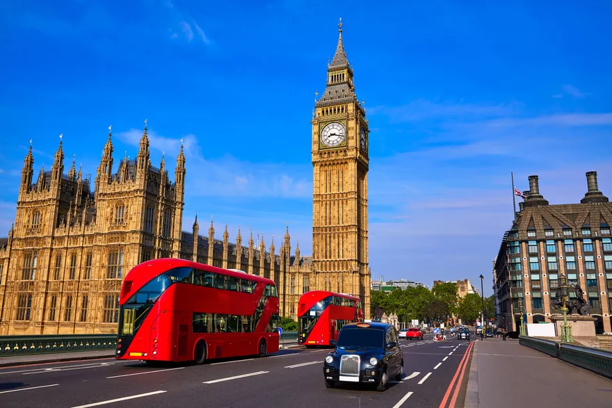 El Big Ben y el Palacio de Westminster en Londres con autobuses rojos de dos pisos y un taxi negro en el puente